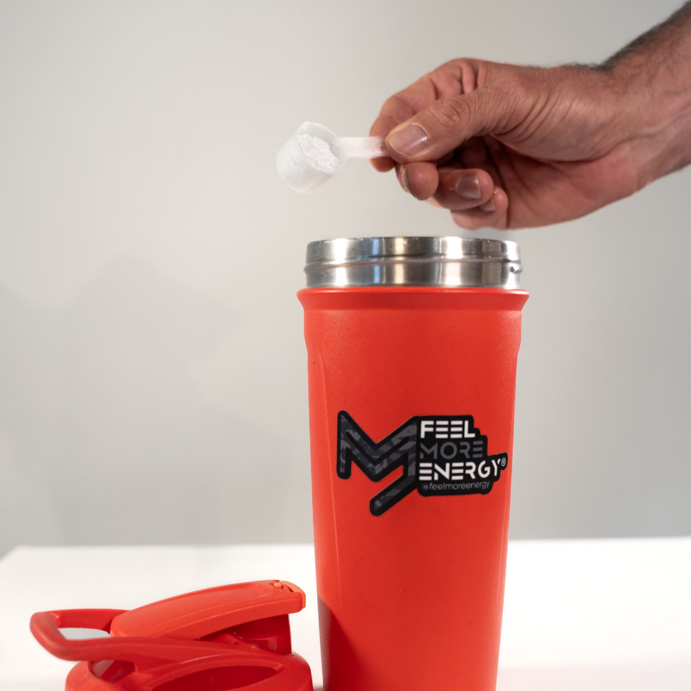Pouring Feel More Energy creatine monohydrate into a shaker bottle — easy mixing for pre or post-workout intake