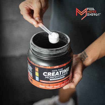 Person holding a jar of creatine monohydrate powder with a scoop, featuring 'Feel More Energy' branding.