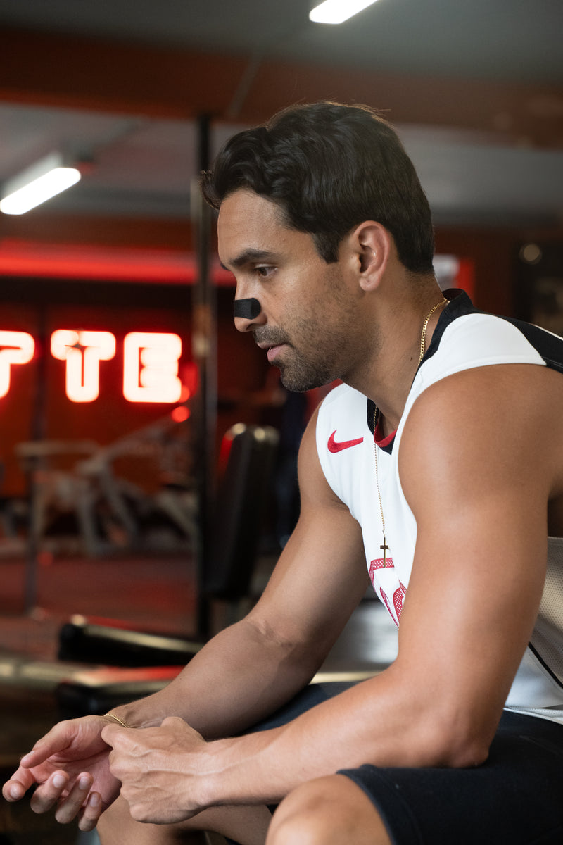 Man sitting in a gym with a red neon sign in the background